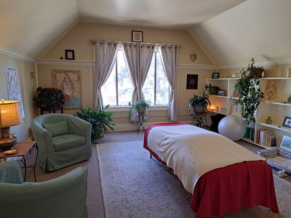 The treatment room with a massage table and tall windows